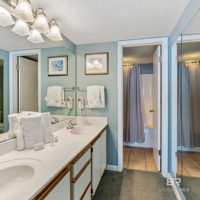 bathroom with tile patterned floors, double vanity, a textured ceiling, and a sink