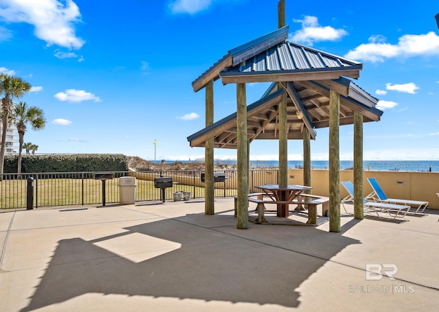 view of patio featuring a gazebo, a water view, and fence