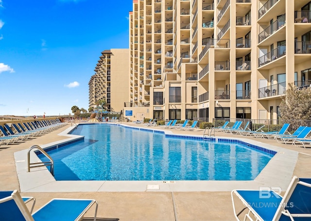 community pool with a patio area and fence