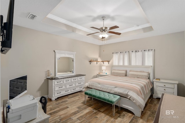 bedroom with wood-type flooring, a raised ceiling, and ceiling fan