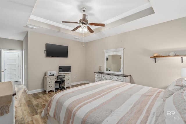 bedroom with a raised ceiling, ceiling fan, and light hardwood / wood-style floors