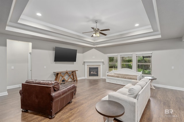 living room with hardwood / wood-style flooring, a raised ceiling, and a tiled fireplace