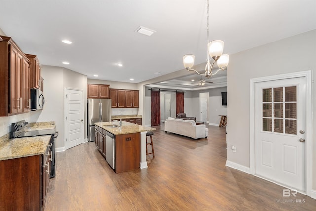 kitchen featuring a kitchen breakfast bar, stainless steel appliances, a center island with sink, a chandelier, and hanging light fixtures