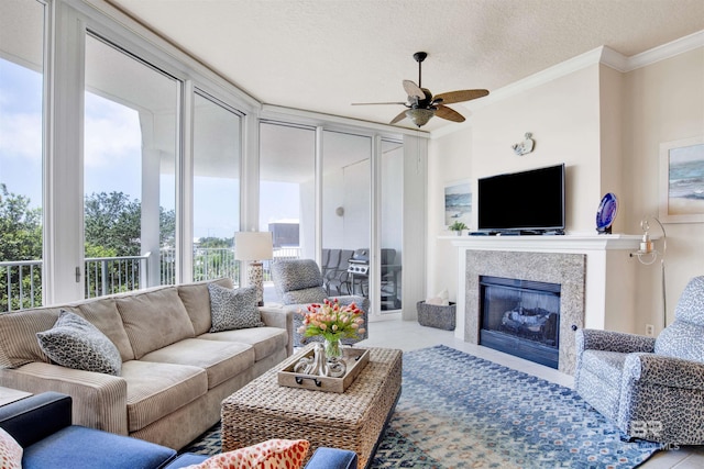 living room featuring crown molding, a textured ceiling, light tile patterned floors, ceiling fan, and a high end fireplace