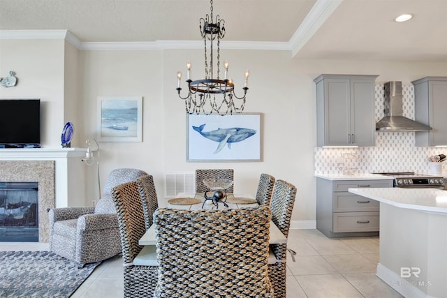 dining space with crown molding, light tile patterned floors, a fireplace, and an inviting chandelier