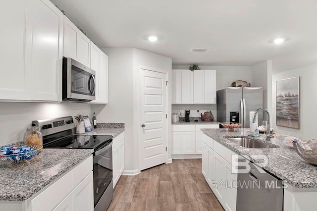 kitchen featuring white cabinets, stainless steel appliances, sink, and light hardwood / wood-style flooring