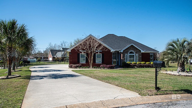 view of front facade featuring brick siding, concrete driveway, a front yard, and fence