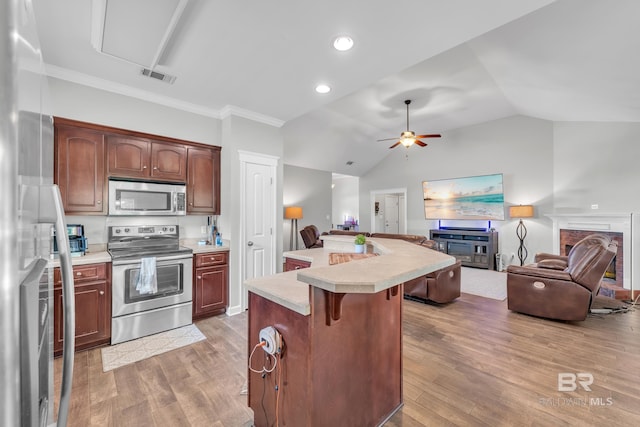 9194 Labrador Trl, Theodore, AL 36582 - kitchen featuring stainless steel appliances, light countertops, open floor plan, a breakfast bar area, and wood finished floors