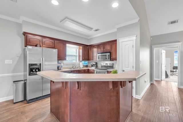 9194 Labrador Trl, Theodore, AL 36582 - kitchen with stainless steel appliances, light countertops, a breakfast bar area, light wood-type flooring, and ornamental molding