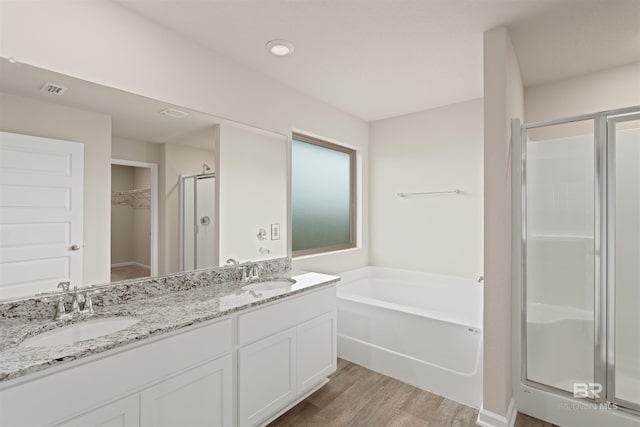 bathroom featuring hardwood / wood-style flooring, separate shower and tub, and dual bowl vanity