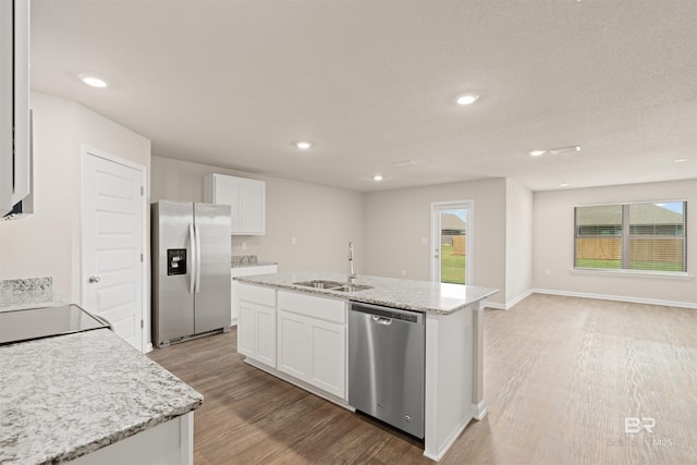 kitchen featuring appliances with stainless steel finishes, light hardwood / wood-style floors, sink, an island with sink, and white cabinets