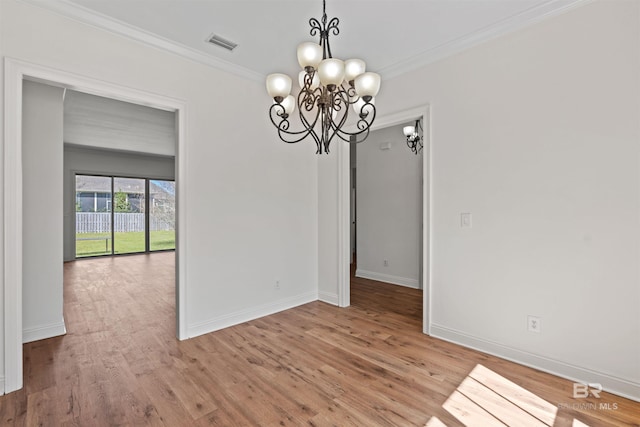 unfurnished dining area featuring visible vents, ornamental molding, wood finished floors, an inviting chandelier, and baseboards