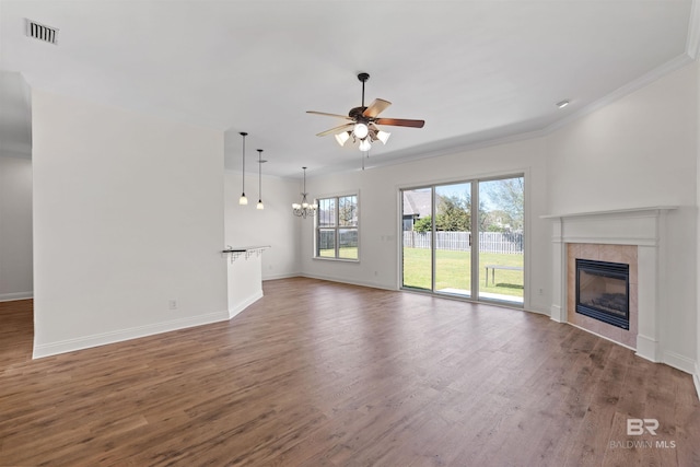 unfurnished living room with visible vents, ceiling fan with notable chandelier, wood finished floors, and a tile fireplace