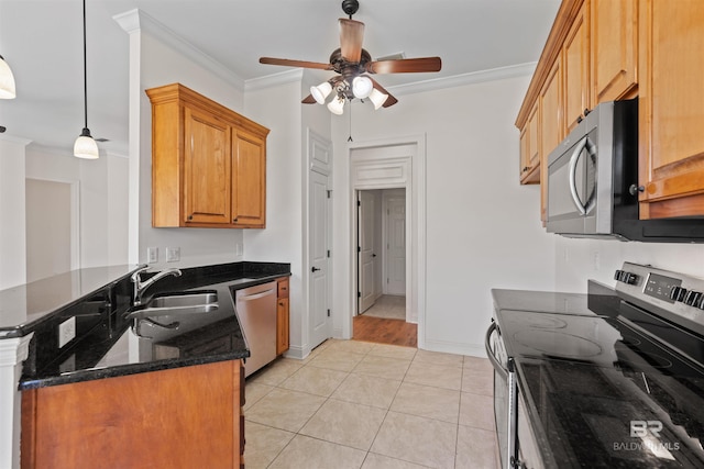 kitchen with dark stone counters, ornamental molding, a peninsula, stainless steel appliances, and a sink