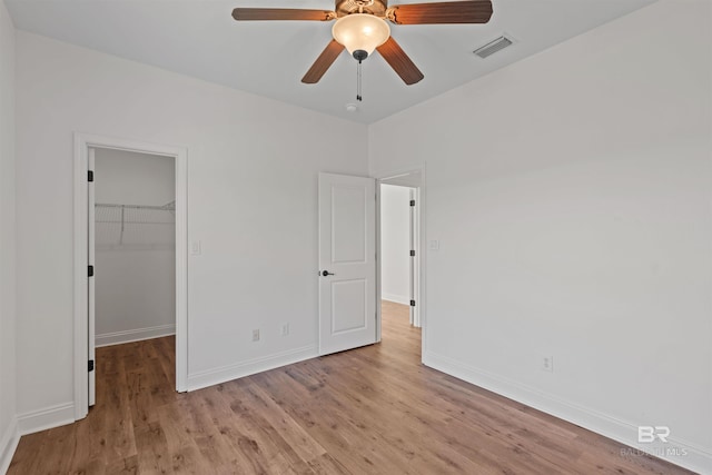 unfurnished bedroom with visible vents, baseboards, wood finished floors, and a spacious closet