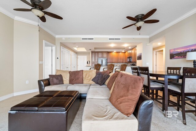 carpeted living room with crown molding and ceiling fan