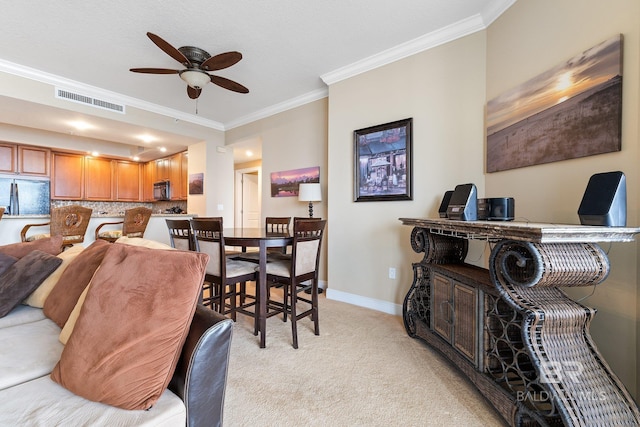 dining room featuring crown molding, light colored carpet, and ceiling fan