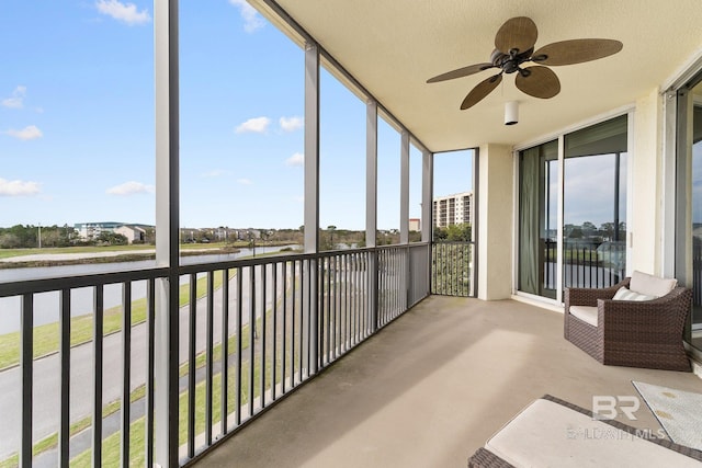 unfurnished sunroom with a water view and ceiling fan