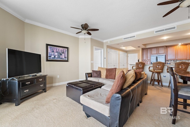 living room with crown molding, light colored carpet, and ceiling fan