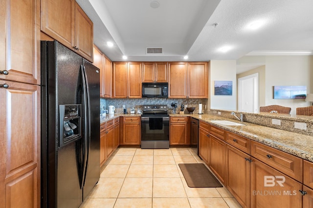 kitchen featuring sink, light tile patterned floors, light stone countertops, decorative backsplash, and black appliances