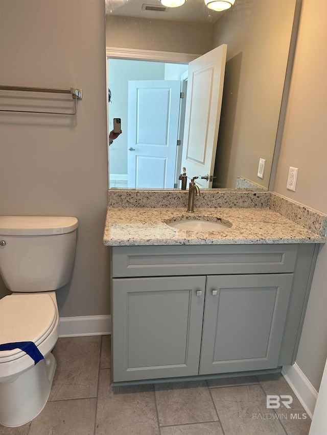 half bathroom featuring toilet, baseboards, and vanity