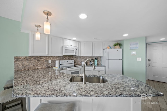 kitchen featuring white appliances, light wood-type flooring, sink, and kitchen peninsula