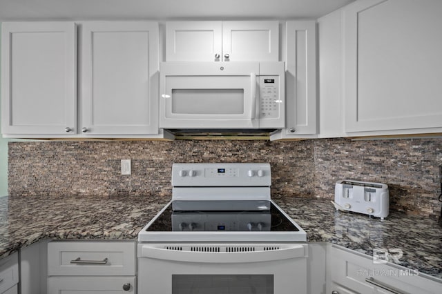 kitchen featuring white appliances, tasteful backsplash, dark stone countertops, and white cabinets