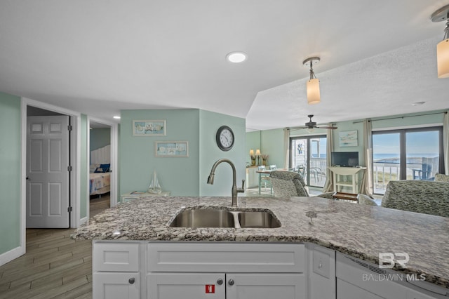 kitchen featuring sink, decorative light fixtures, white cabinets, light stone counters, and light hardwood / wood-style floors