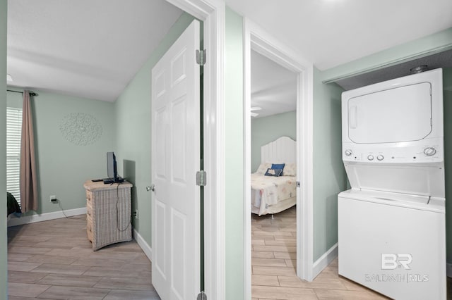 laundry area with light hardwood / wood-style floors and stacked washing maching and dryer