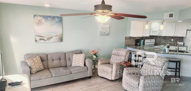 living room with light hardwood / wood-style flooring, sink, and ceiling fan