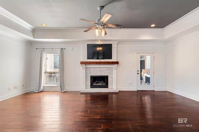 unfurnished living room with hardwood / wood-style floors, ceiling fan, a stone fireplace, and ornamental molding