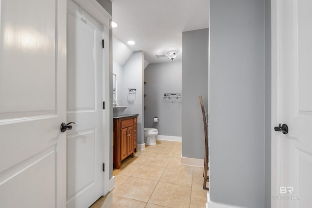 bathroom featuring tile patterned flooring, vanity, lofted ceiling, and toilet