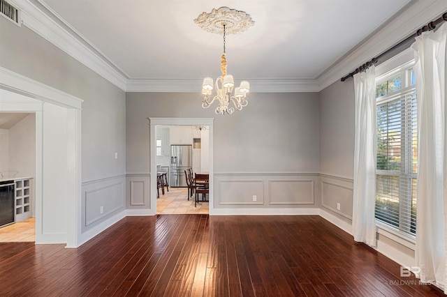 unfurnished dining area with hardwood / wood-style flooring, a notable chandelier, and crown molding