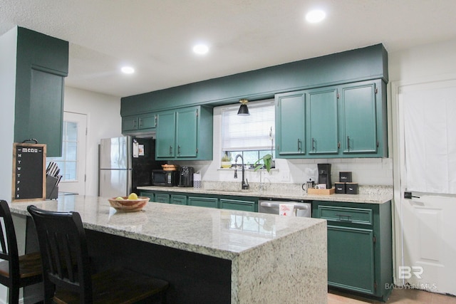 kitchen with sink, stainless steel appliances, light stone counters, a breakfast bar area, and decorative backsplash