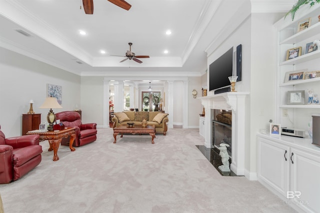 living room with a premium fireplace, light carpet, a tray ceiling, crown molding, and ceiling fan