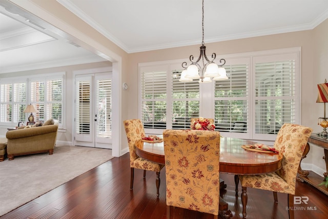 carpeted dining room with crown molding and a notable chandelier