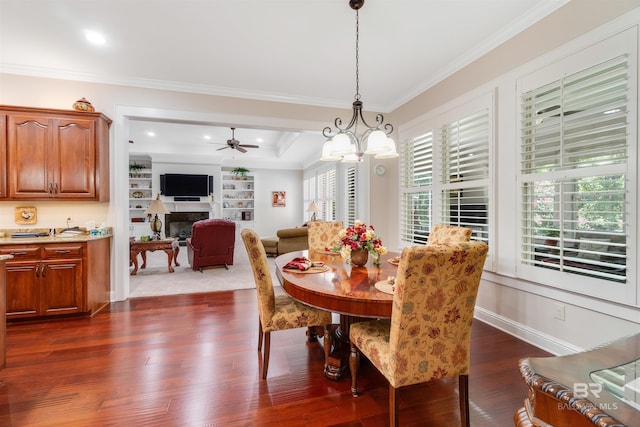 dining area featuring ceiling fan with notable chandelier, a tray ceiling, dark hardwood / wood-style floors, and crown molding