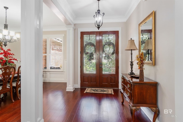 foyer with crown molding, dark wood-type flooring, a wealth of natural light, and a chandelier