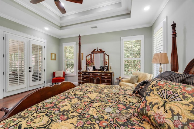 bedroom with a tray ceiling, crown molding, hardwood / wood-style flooring, and access to exterior