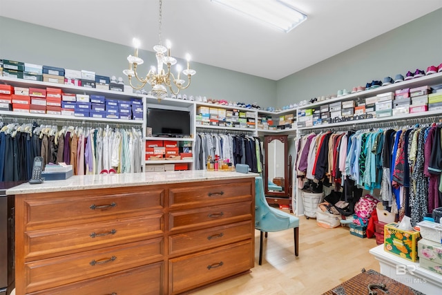 walk in closet with light hardwood / wood-style flooring and an inviting chandelier