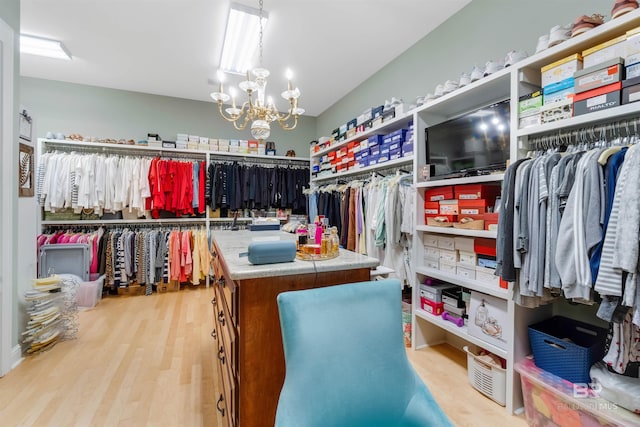 walk in closet with an inviting chandelier and light hardwood / wood-style floors