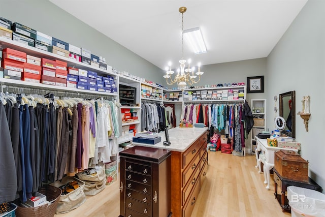 walk in closet with light wood-type flooring, vaulted ceiling, and a chandelier