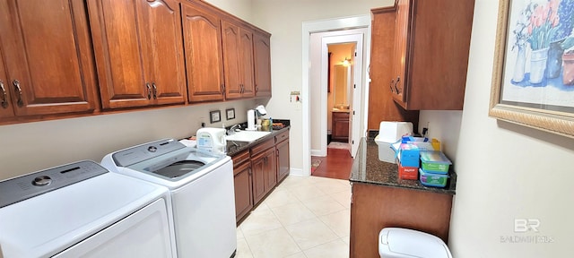 washroom featuring washing machine and dryer, cabinets, sink, and light tile patterned floors