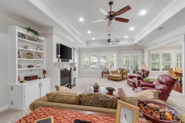 living room with light carpet, a raised ceiling, and ceiling fan