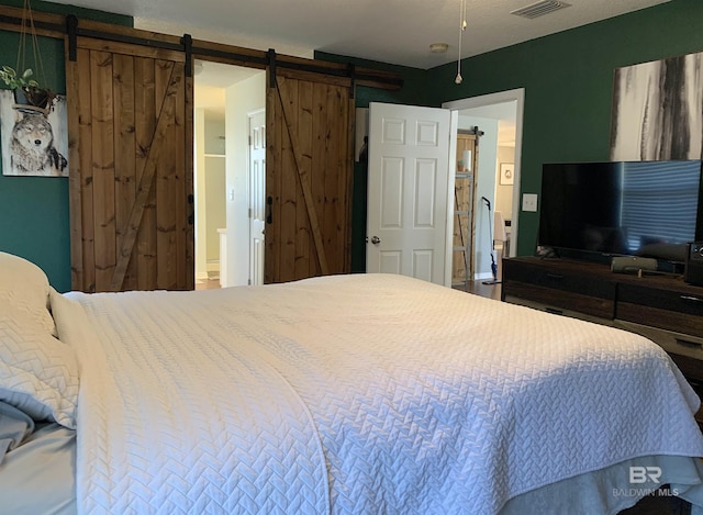 bedroom featuring visible vents and a barn door