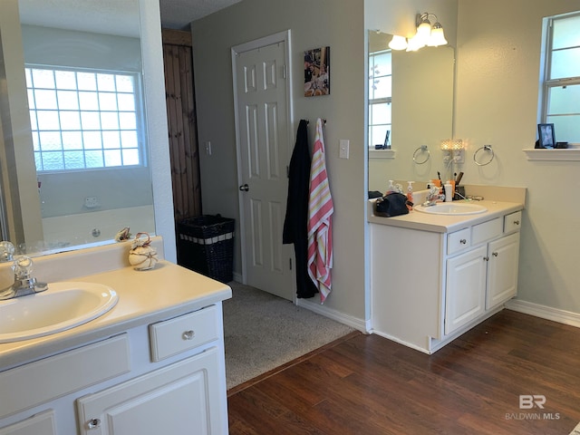 full bath with a sink, baseboards, wood finished floors, and two vanities