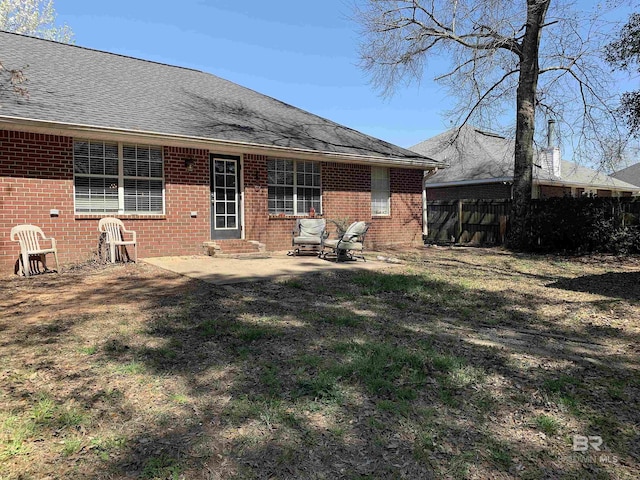 back of house with brick siding, fence, a patio area, and roof with shingles