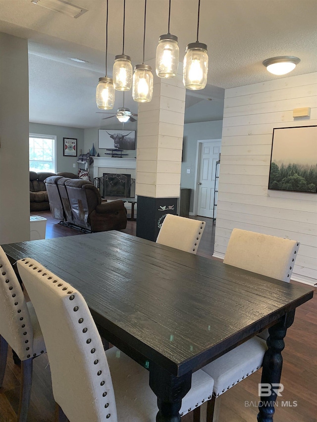 dining room with visible vents, a fireplace, wooden walls, ornate columns, and dark wood-type flooring