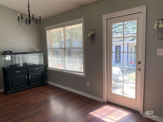 dining space featuring baseboards, dark wood finished floors, a notable chandelier, and a wealth of natural light