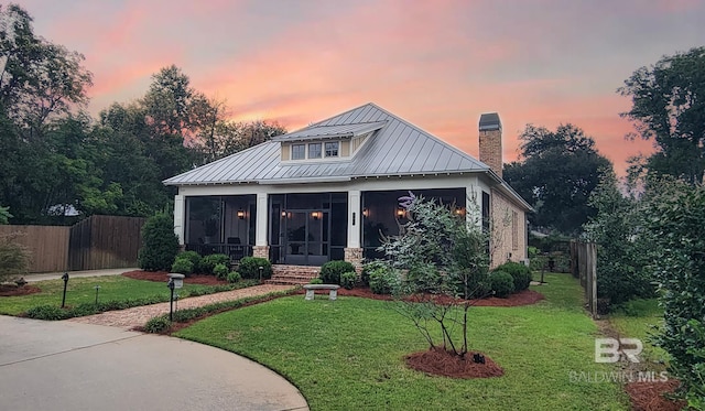 view of front of house with a sunroom and a lawn